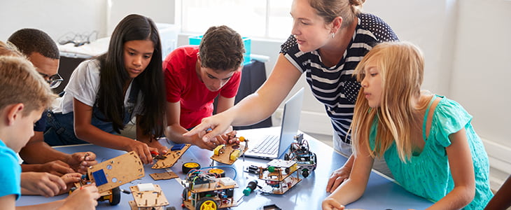 Children smile and work on a robotics project
