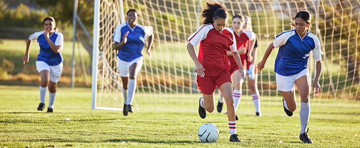 Young soccer players run in front of a goal