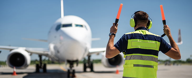 An airport employe directs a plane to a gate