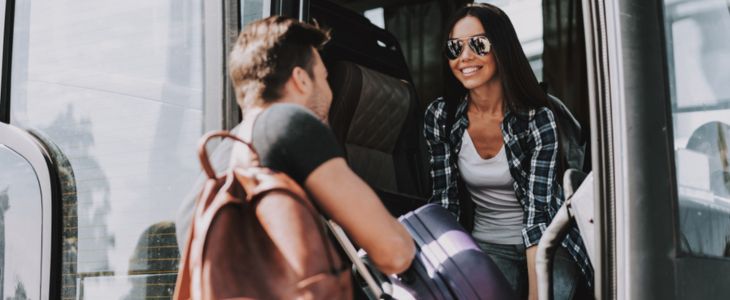 a man helps a woman load her suitcase onto a bus