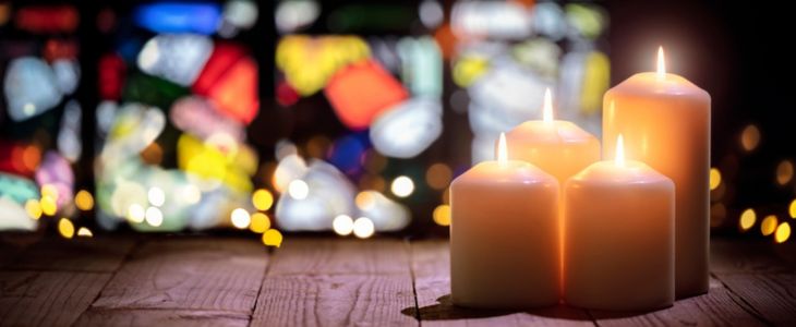 candles lit in front of a stained glass window