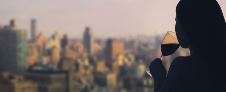 silhouette of a woman drinking wine in front of the new york city skyline