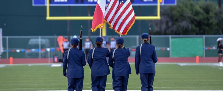a group of ROTC cadets perform colors at a football game