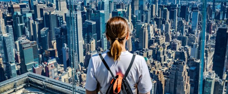 a woman looks at the new york city skyline from a high vantage point