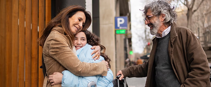 A family hugging and smiling on a city sidewalk