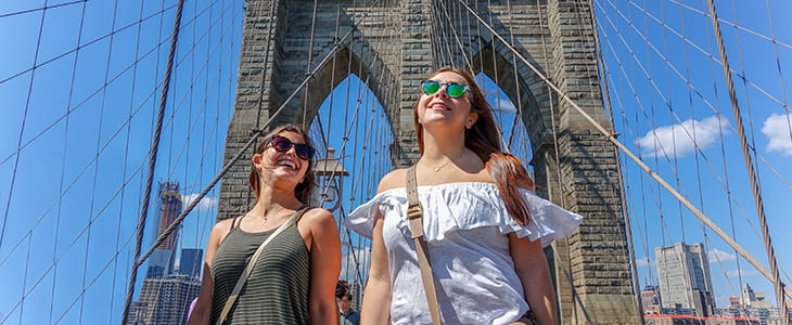 NYC tourists walk on the Brooklyn Bridge